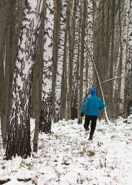 All'uomo piace correre nella foresta invernale.
