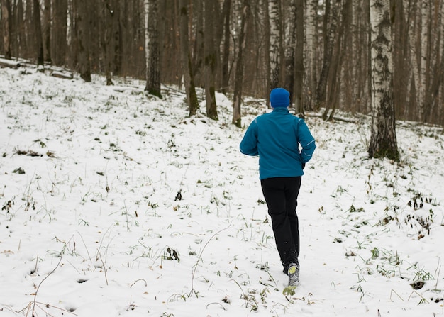 All'uomo piace correre nella foresta invernale.