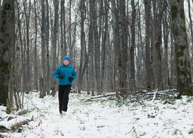 All'uomo piace correre nella foresta invernale.