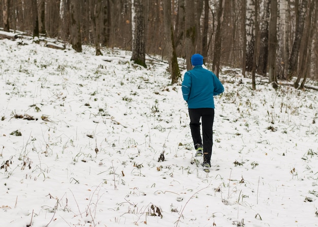 All'uomo piace correre nella foresta invernale.