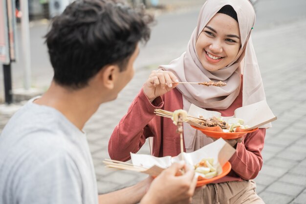 Alla coppia piace mangiare pollo satay che hanno comprato dal venditore di cibo di strada in Indonesia