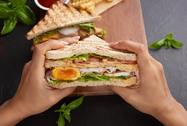 Alla griglia e panino con pancetta, uovo fritto, pomodoro e lattuga serviti sul tagliere di legno