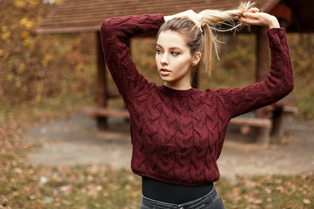 Alla moda bella giovane donna in un maglione vintage all'aperto nella foresta in una giornata autunnale