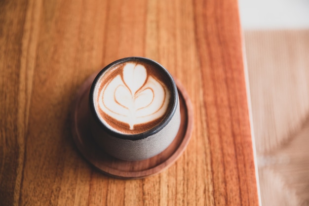 Alla moda grigio elegante tazza di cappuccino caldo con latte art sul fondo della tavola in legno.