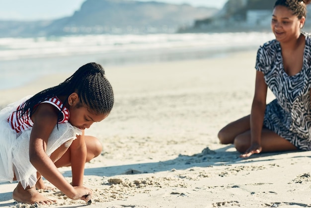 Alla ricerca di conchiglie Inquadratura di una madre e della sua piccola figlia che giocano nella sabbia in spiaggia