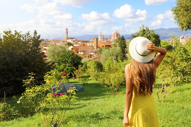 Alla scoperta di Firenze. Vista posteriore di giovane ragazza turistica guardando il paesaggio urbano di Firenze tra gli alberi. Turismo in Toscana.