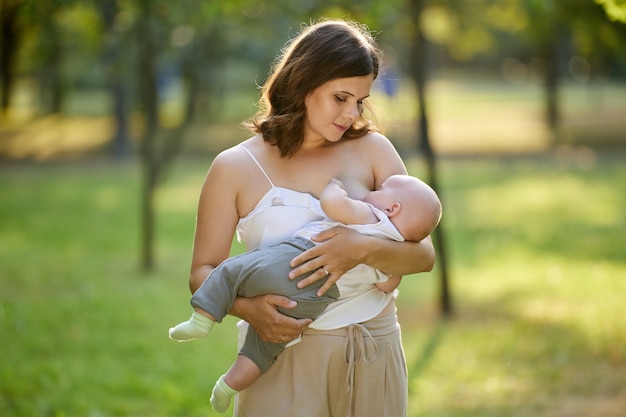 Allattando al seno in un parco pubblico la giovane madre dà il seno al suo bambino mentre cammina