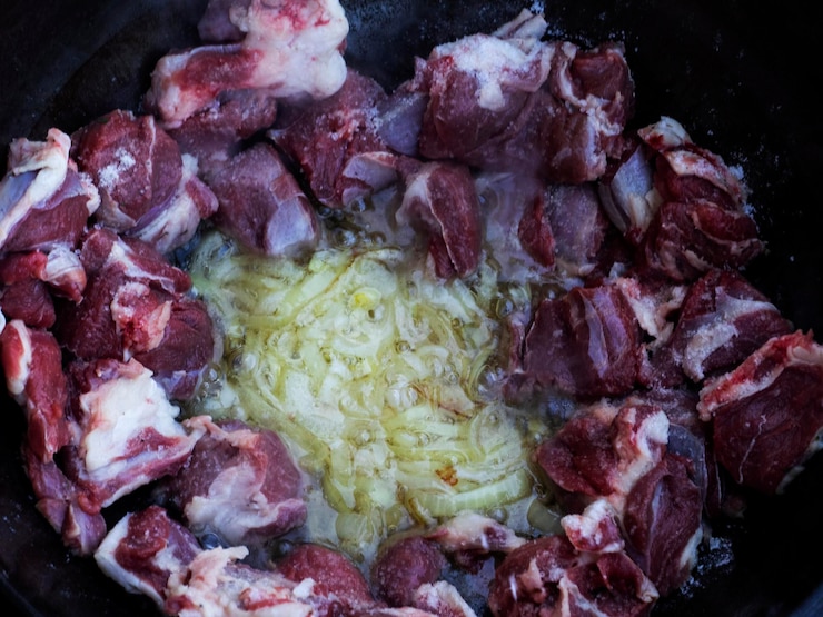 Foto alle cipolle arrostite in calderone si aggiungono pezzi di agnello e si arrostiscono per ottenere una crosta dorata di pilaf