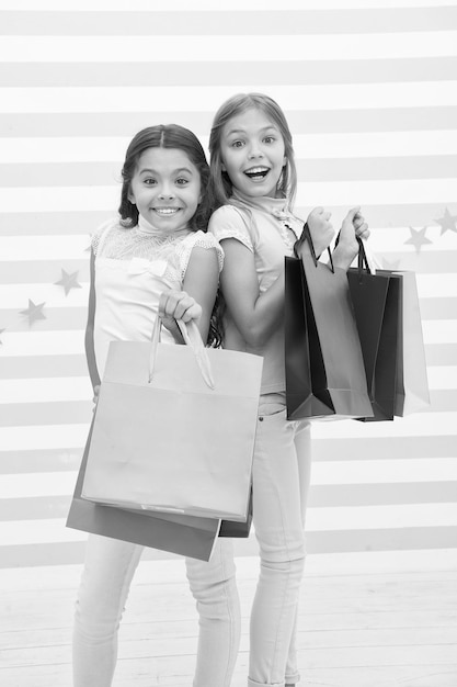 Alle ragazze piace fare shopping Le bambine felici tengono le borse della spesa Divertiti a fare shopping con la migliore amica o sorella Felicità da ragazzina I bambini felici portano pacchetti di mazzi Shopping con il concetto di migliore amico