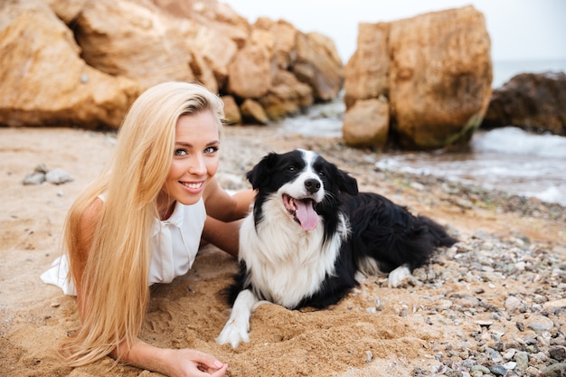 Allegra affascinante giovane donna sdraiata e abbracciando il suo cane sulla spiaggia