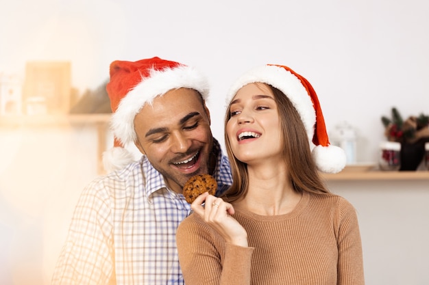 Allegra coppia felice attraente in cappelli di Babbo Natale