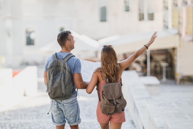 Allegra coppia innamorata che si diverte e si gode le vacanze estive mentre cammina ed esplora una città mediterranea.