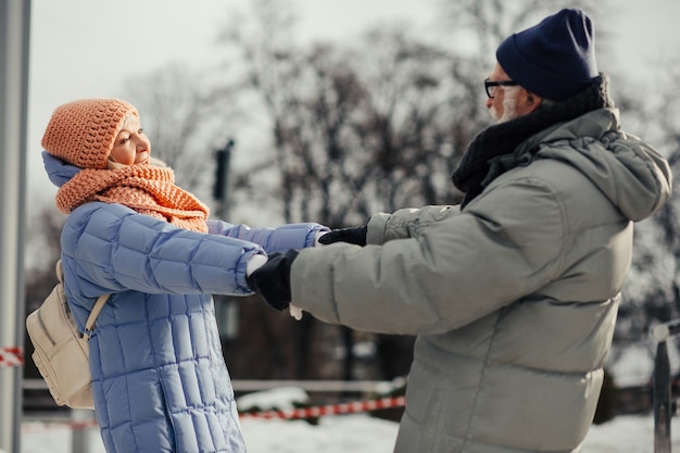 Allegra coppia romantica di persone anziane in abiti invernali che si rilassano all'aperto e ballano