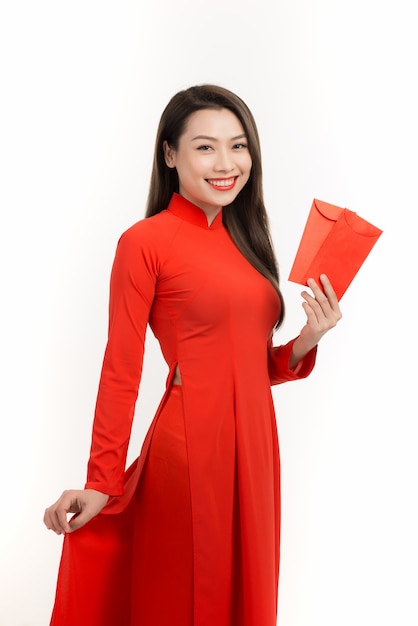 Allegra donna asiatica che indossa la tradizione del Vietnam Ao dai mentre tiene in mano buste rosse su bianco.
