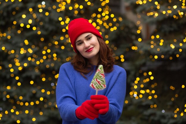 Allegra donna bruna con caramelle all'albero di Natale