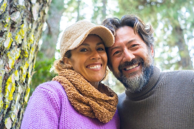 Allegra e felice coppia adulta sorridono insieme al camper in attività ricreative all'aperto con boschi e alberi forestali sullo sfondo Persone e concetto di turismo stile di vita Uomo e donna