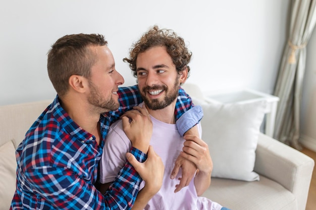 Allegra giovane coppia gay seduta insieme Due affettuosi amanti maschi che sorridono allegramente mentre si abbracciano Giovane coupé gay che è romantico