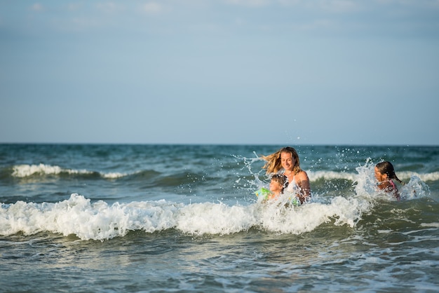 Allegra giovane madre nuota nel mare con le sue affascinanti figlie piccole e godersi il tanto atteso fine settimana in una soleggiata giornata estiva