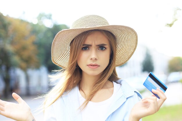 Allegra giovane ragazza ottimista in piedi all'aperto, tenendo in mano la carta di credito.