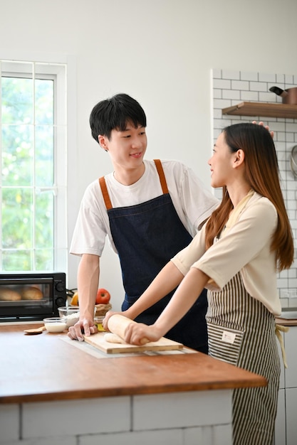 Allegre coppie asiatiche che fanno la pasta si divertono a cuocere insieme la pasta in cucina