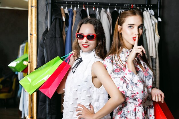 Allegre ragazze felici di successo che tengono borse della spesa colorate in un centro commerciale di moda concetto di consumismo Black Friday vendita vita ricca