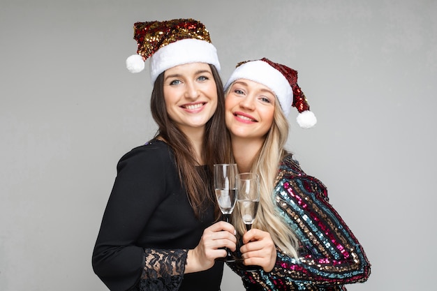 Allegre sorelle caucasiche beve champagne e si rallegrano, immagine isolata sul muro bianco