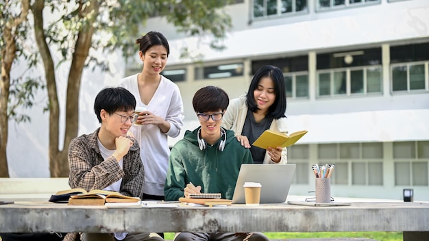 Allegri giovani studenti universitari asiatici stanno facendo brainstorming e stanno lavorando al loro progetto scolastico