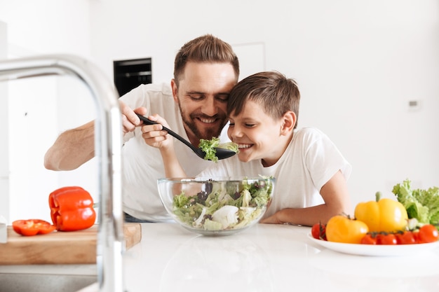 Allegro giovane padre papà che cucina con suo figlio