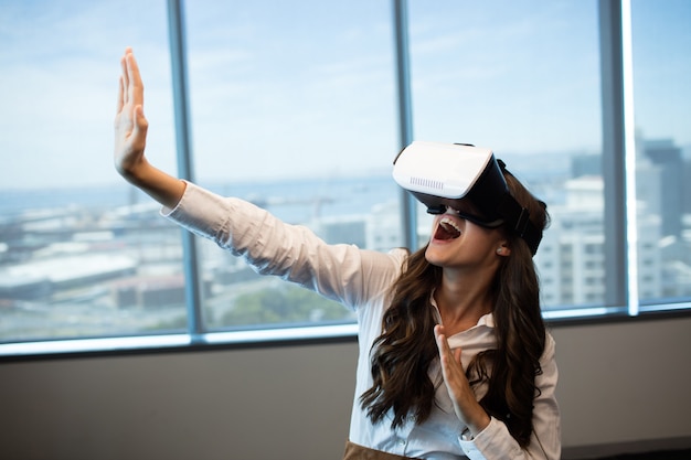Allegro imprenditrice gesticolando durante l'utilizzo di occhiali per realtà virtuale