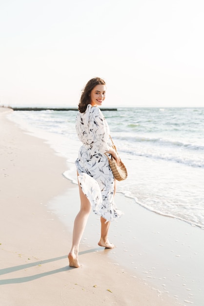 allegro positivo felice giovane bella donna in spiaggia a piedi in una bella mattina di sole.