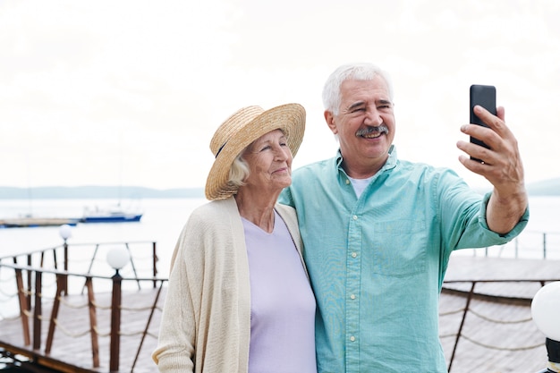 Allegro senior marito e moglie facendo selfie con lo smartphone il giorno d'estate