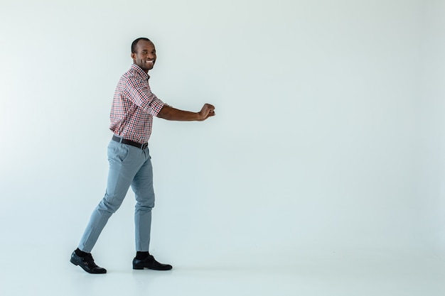 Allegro uomo afroamericano adulto che spinge un carrello mentre vi godete lo shopping