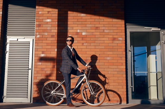 Allegro uomo d'affari in sella a bici su strada