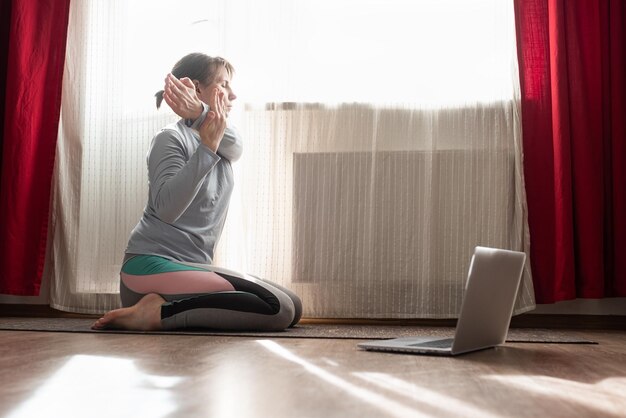 Allenamento a casa e yoga Giovane donna che allunga le mani seduta sul pavimento