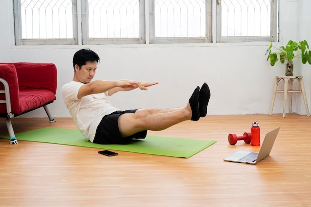 Allenamento a casa Uomo sportivo che fa yoga plank mentre guarda il tutorial online sul laptop