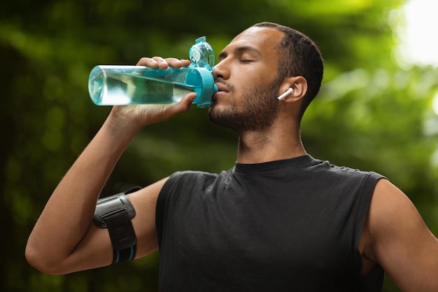 Allenamento atletico dell'acqua potabile dell'uomo di colore al parco