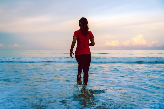 Allenamento corrente della ragazza che pareggia sulla spiaggia di mattina.