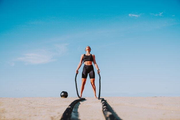 Allenamento di allenamento funzionale sulla spiaggia, donna in forma e atletica che fa sport all'aria aperta