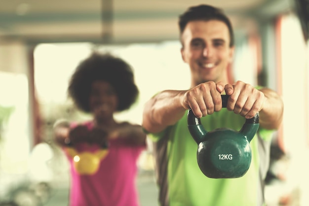 allenamento di coppia sana con manubri di sollevamento pesi in palestra crossfit donna afroamericana con acconciatura afro