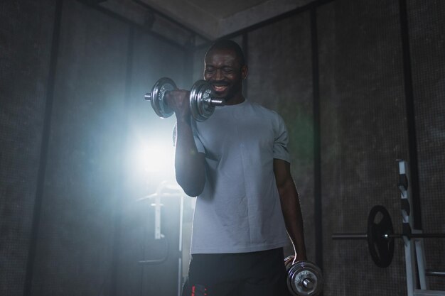 allenamento di fitness in palestra uomo afroamericano bodybuilder che raccoglie manubri in palestra allenamento di peso