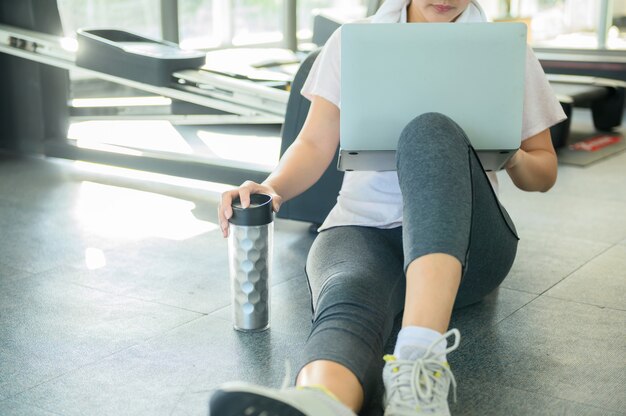 Allenamento donna asiatica e lavoro online da solo in palestra.