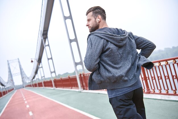 Allenamento mattutino primo piano di un giovane in abbigliamento sportivo che si esercita mentre fa jogging sul