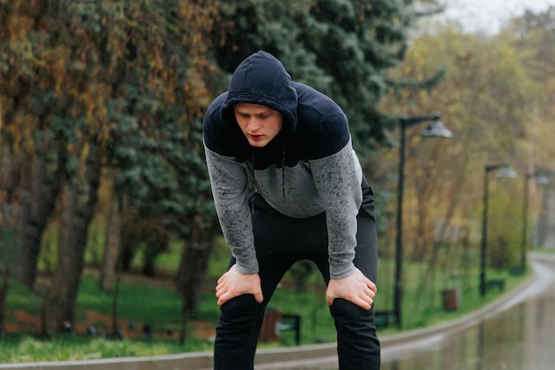 Allenamento negli elementi un ragazzo regime di fitness all'aperto in un giorno di pioggia un giovane uomo allenamento nel r