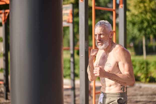 Allenamento. Un uomo maturo dai capelli grigi che si esercita nel parco