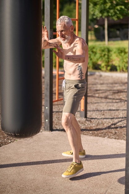 Allenamento. Un uomo maturo dai capelli grigi che si esercita nel parco