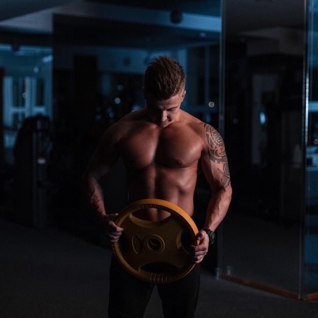 Allenamento uomo senza camicia in palestra. Ragazzo potente con un corpo forte e sano