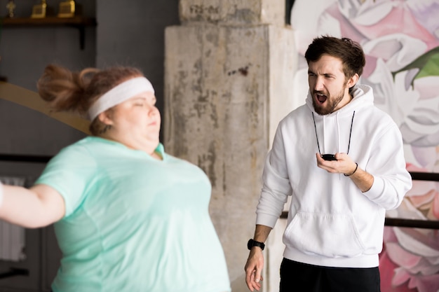 Allenatore arrabbiato che prepara donna obesa