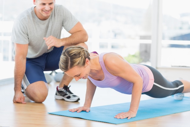 Allenatore che assiste la donna con push up