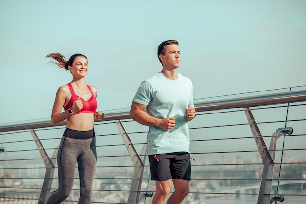 Allenatore con atleta femminile che corre sul ponte della città al mattino