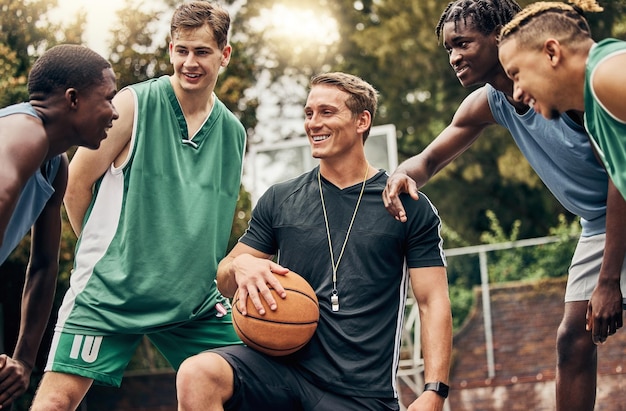 Allenatore di basket che parla con la sua squadra durante una sessione di allenamento su un campo all'aperto Motivazione del lavoro di squadra e discorso di ispirazione dell'allenatore per la squadra di basket che si diverte e impara in un gioco sportivo